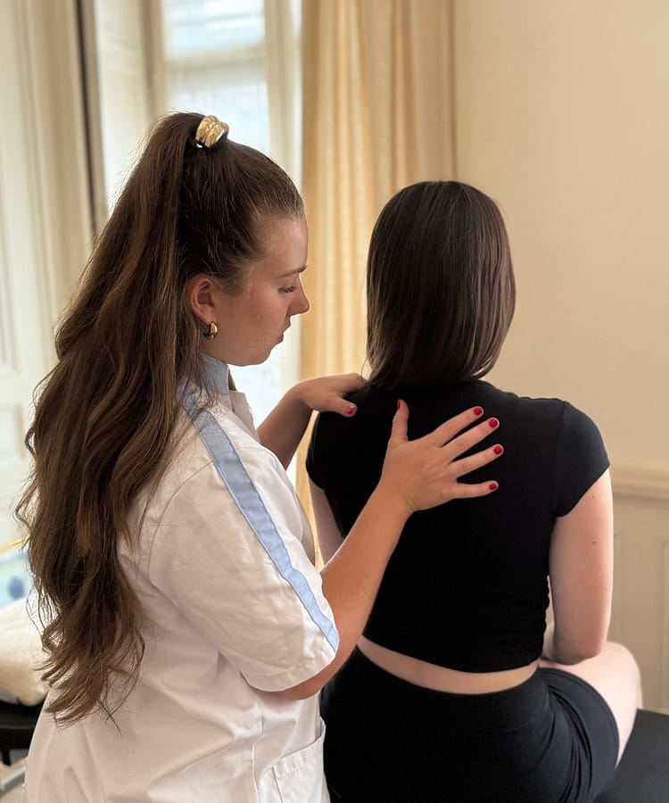 Ostéopathe palpant le haut du dos d’une patiente.